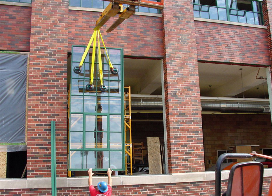 A large window being installed in the field on a brick building.