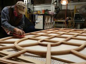 A worker sands a monumental arch window for Dunster Hall.