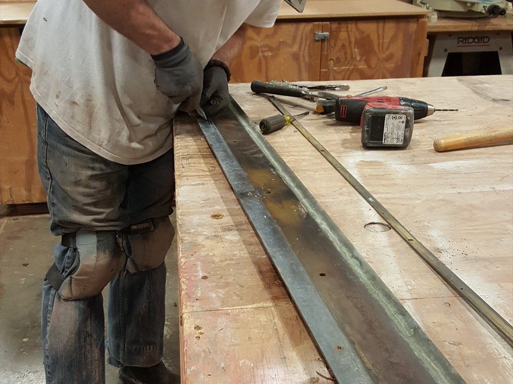 A worker restores a metal window structure.
