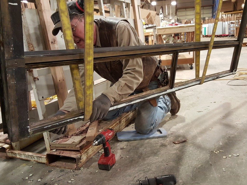 A worker restores a metal window structure.