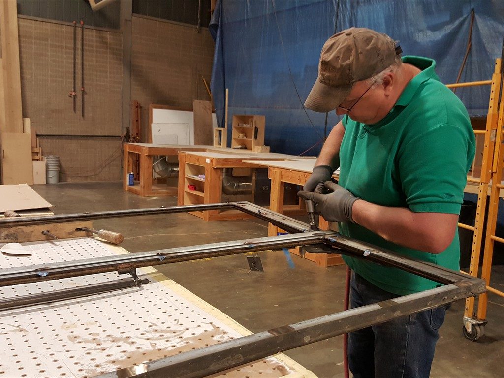 A worker restores a metal window structure.