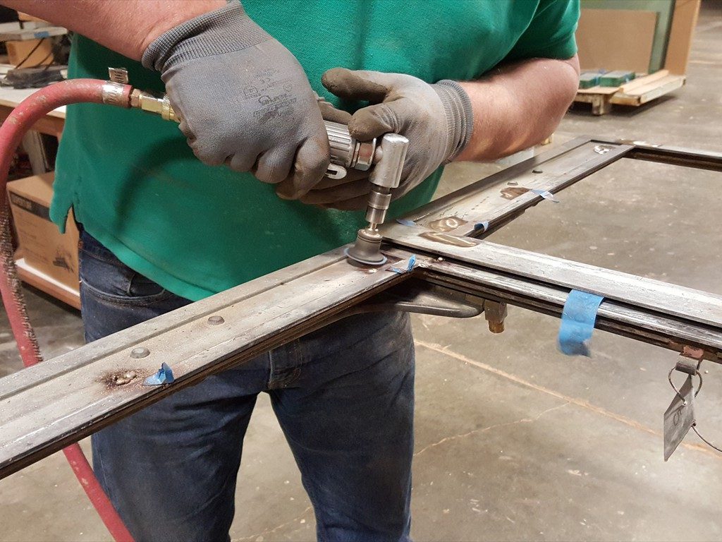 A worker restores a metal window structure.