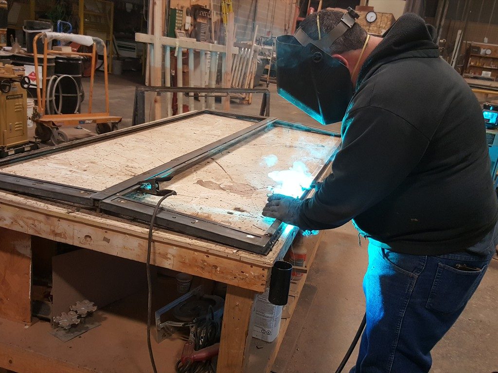 A worker restores a metal window structure.