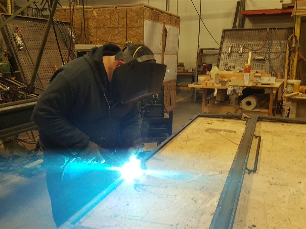 A worker restores a metal window structure.