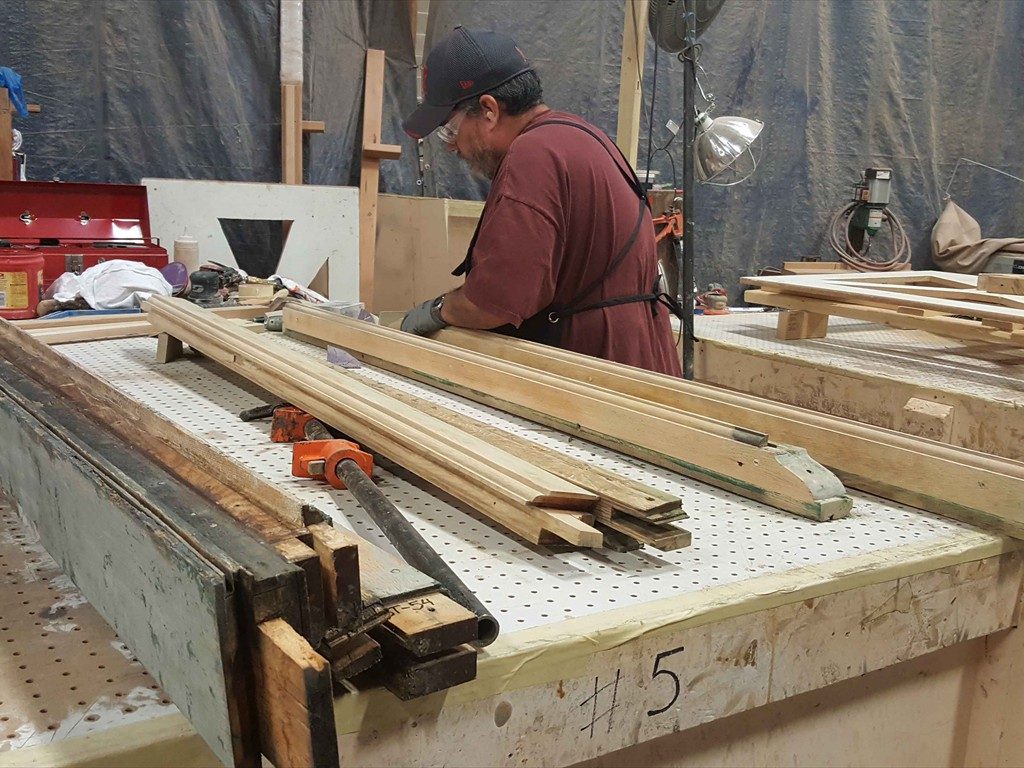 A craftsperson works with wood window parts.