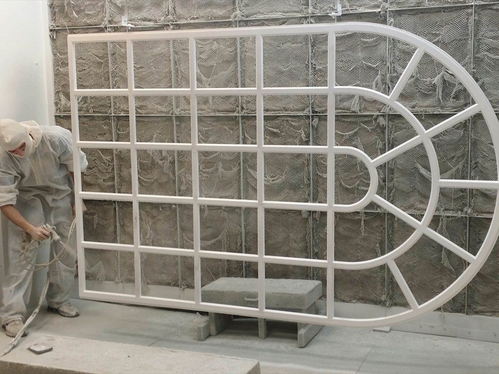 A worker paints a monumental arch window for Dunster Hall.