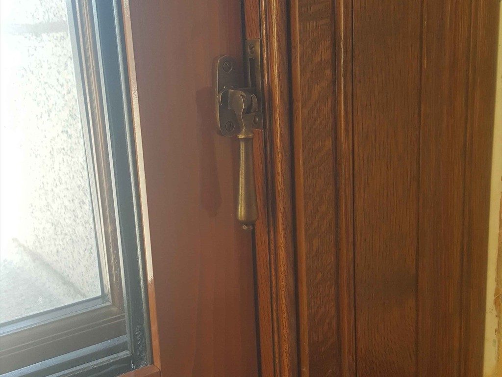Brass hardware installed on a wood window frame.