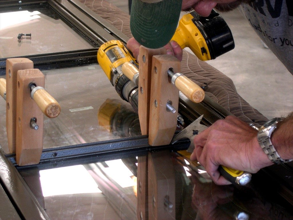 A worker restores a metal window frame.
