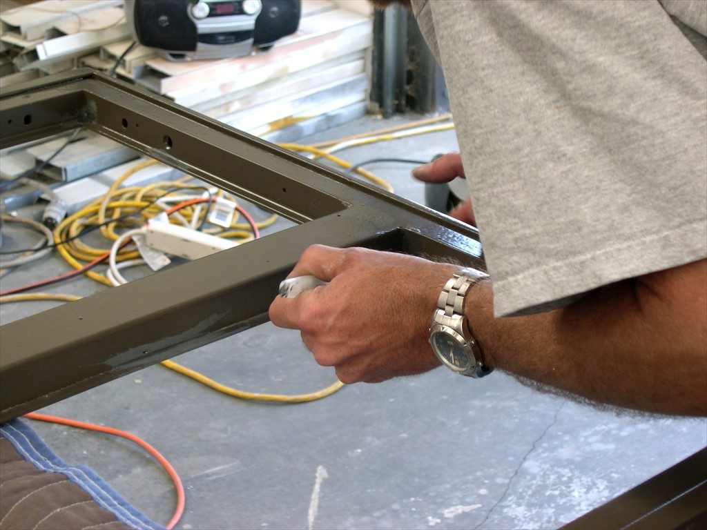 A worker restores a metal window frame.