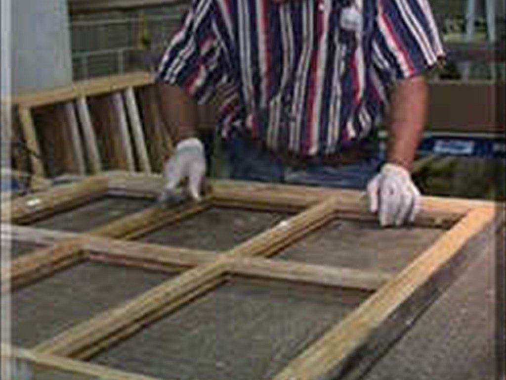 A worker with a window sash in the shop during restoration.