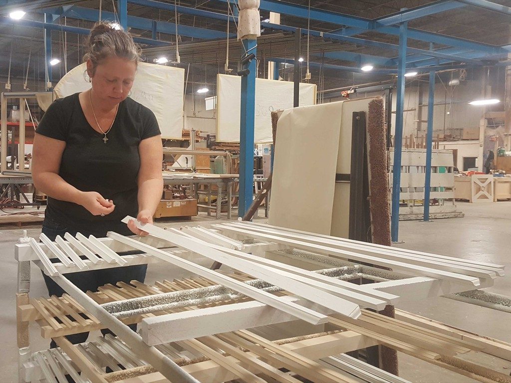 A worker prepares a wood window component in the shop.