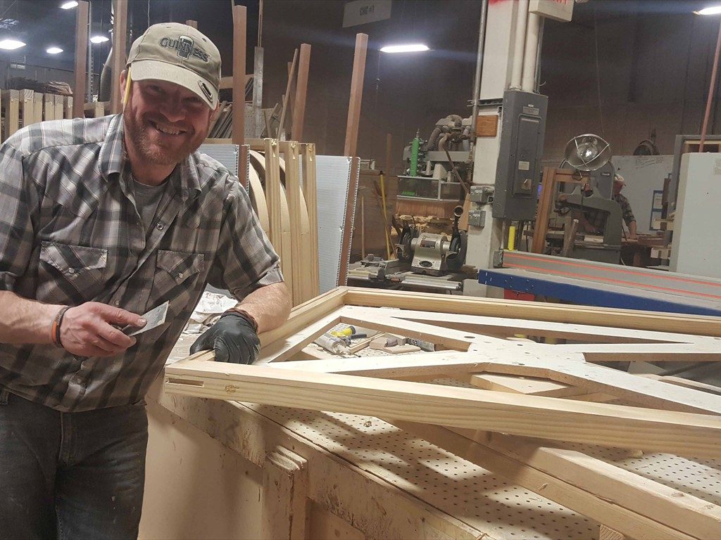 A worker prepares a wood window component in the shop.